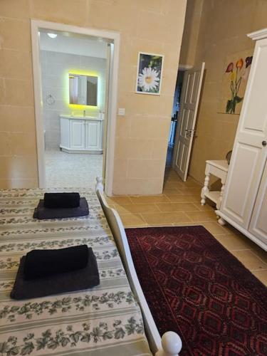 a room with two beds and a bathroom with a mirror at Unique Farmhouse in the Heart of Gozo - Nadur in Nadur
