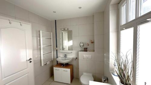 ein weißes Bad mit einem Waschbecken und einem WC in der Unterkunft Müggenburger Weg  " Meeresrauschen 2 " in Zingst