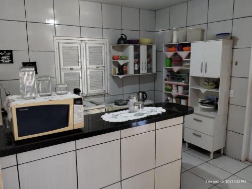 a kitchen with a microwave on a black counter top at Aconchego do bens in Cruz
