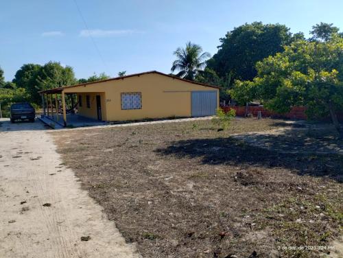 ein kleines gelbes Gebäude in der Mitte eines Gartens in der Unterkunft Aconchego do bens in Cruz