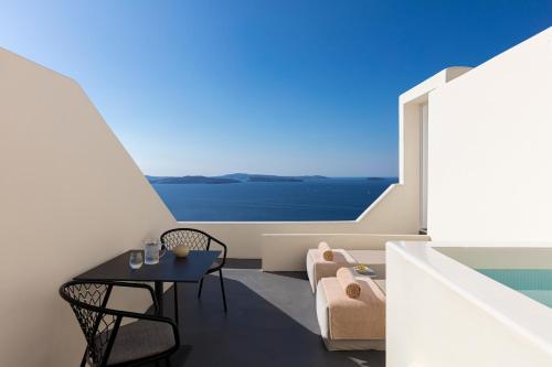 a room with a table and chairs and a large window at Canaves Oia Suites - Small Luxury Hotels of the World in Oia