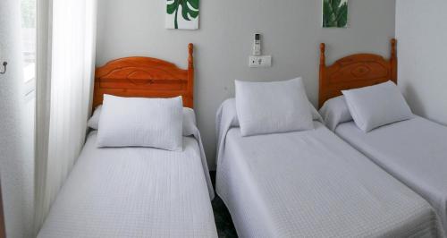 two twin beds in a room with white walls at Hostal Al-Andalus in La Guijarrosa