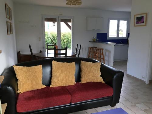 ein schwarzes Sofa mit Kissen im Wohnzimmer in der Unterkunft Maison de vacances au calme in Angles