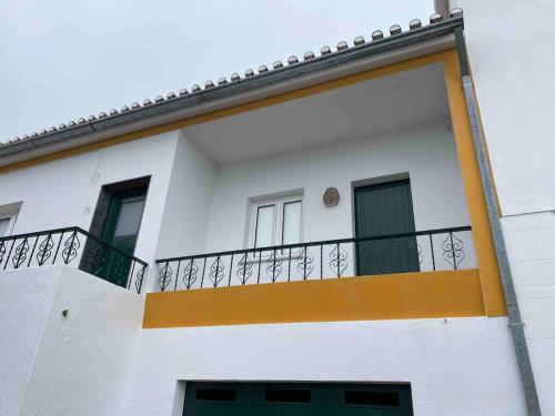 a white building with an orange and white balcony at Casa da Bisa in Carreiras