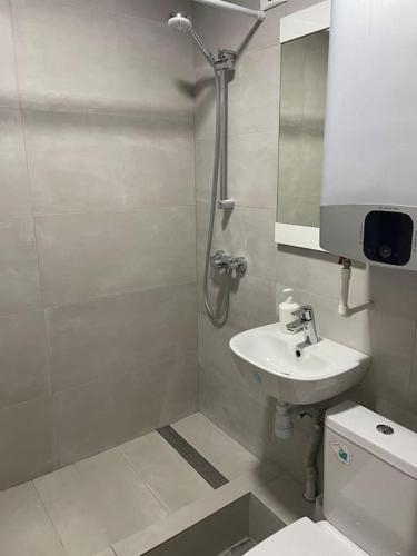 Un baño con ducha, lavabo e inodoro. en Уютная студия в центре Кишинёва, en Chişinău