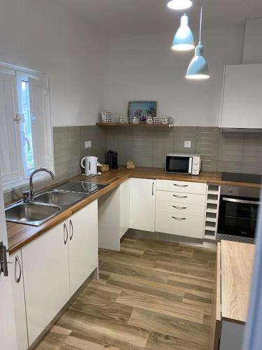 a kitchen with white cabinets and a wooden floor at Casa da Bisa in Carreiras
