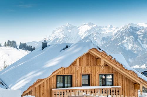 a log cabin in the mountains with snow on the roof at Poolchalet Dachsteinblick in Pruggern