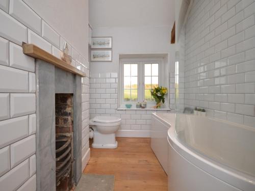 y baño con chimenea, aseo y bañera. en 2 bed property in Ilminster Somerset 56523, en Ilminster