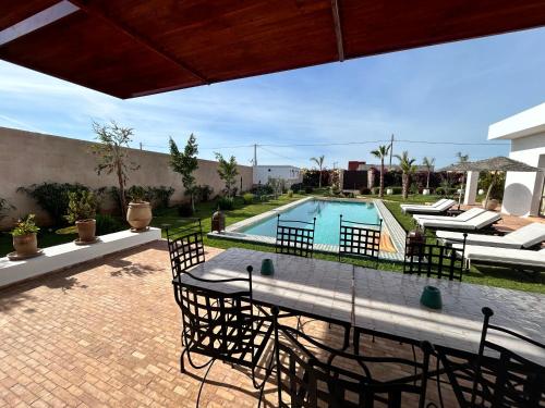 a patio with a table and chairs and a swimming pool at Villa Ehzzara piscine chauffée in Essaouira