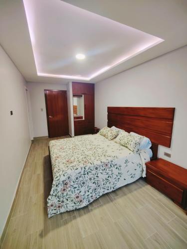 a bedroom with a large bed with a wooden headboard at Quinta Esperanza - Habitación Matrimonial in Loja