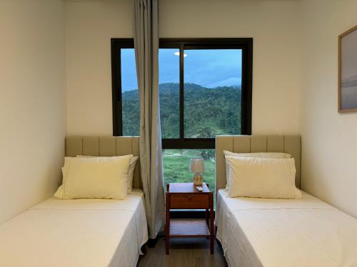 two beds in a room with a window at OKA Praia Brava - Norte in Itajaí