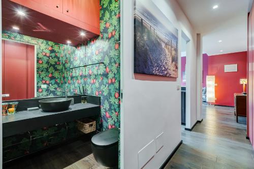 baño con lavabo negro y papel pintado con motivos florales en Music Bridge Apartment, en Roma