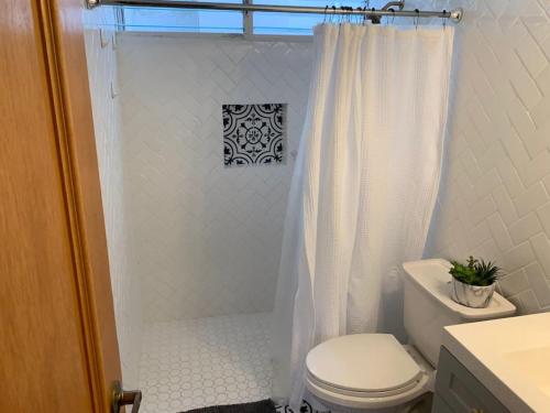 a bathroom with a white shower curtain and a toilet at Attractive Penthouse in Isla Verde in San Juan