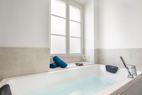 a white bath tub in a bathroom with a window at L'Appartement des Ducs avec Baignoire Double in Nantes