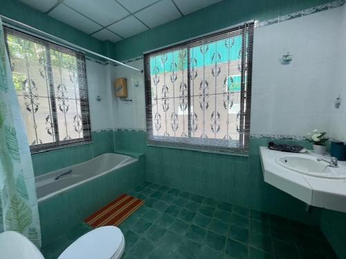 a green bathroom with a tub and a toilet and a sink at Kata Sea Blue Villa in Kata Beach