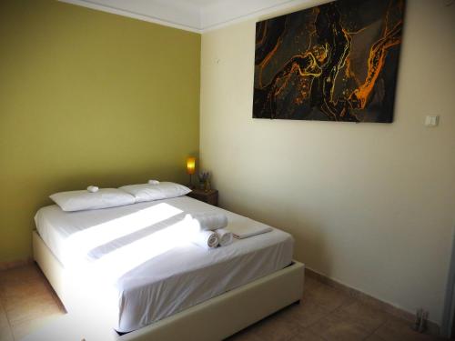 a bedroom with a white bed with a painting on the wall at Melia Luxury Studio in Thessaloniki