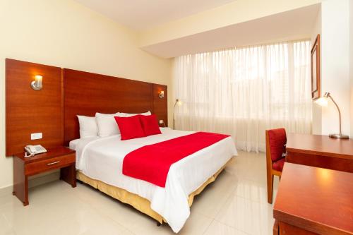 a bedroom with a large bed with a red blanket at Hotel Faranda Express Puerta del Sol Porlamar in Porlamar
