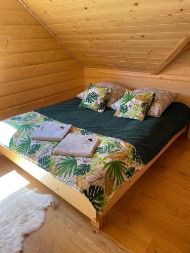 a bed in a wooden cabin with pillows on it at Świerkowe Chatki w Koniakowie in Koniaków