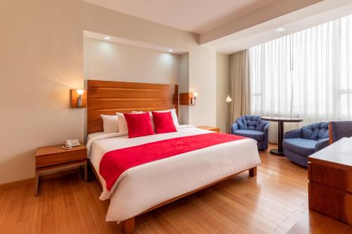 a hotel room with a large bed with red pillows at Hotel Faranda Express Puerta del Sol Porlamar in Porlamar