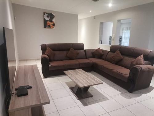Sala de estar con sofá marrón y mesa de centro en Teke's cheerful 3 bed room villa with swimming pool, en East London