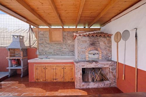 a kitchen with a stove and a sink and a fireplace at La Tirajanera 2 in Vega de San Mateo