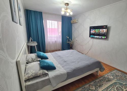a bedroom with a bed with blue pillows and a television at 1 к квартира в Центре Мухита д 128 in Uralsk