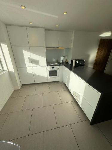 a kitchen with white cabinets and a black counter top at Two bed in Clapham in London