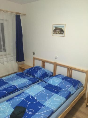a bed with a blue comforter in a bedroom at U Čmeláka in Vyskeř