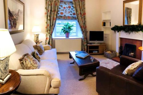 ein Wohnzimmer mit einem Sofa und einem Tisch in der Unterkunft Cosy Wee Cottage St Andrews 20 in Ceres