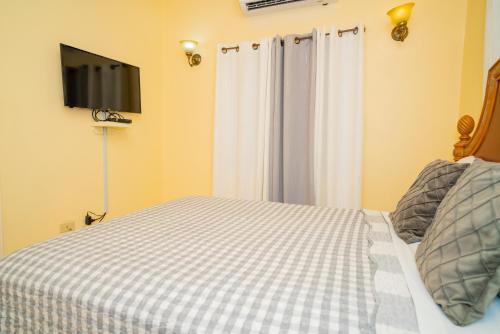 a bedroom with a bed with a tv on the wall at Connie's Comfort Suites in Saint Johnʼs