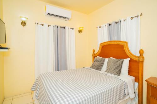 a bedroom with a bed with a wooden headboard and curtains at Connie's Comfort Suites in Saint Johnʼs