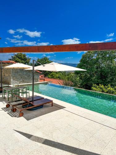 a pool with two chairs and an umbrella next to it at Villa Isobel in Vila Verde