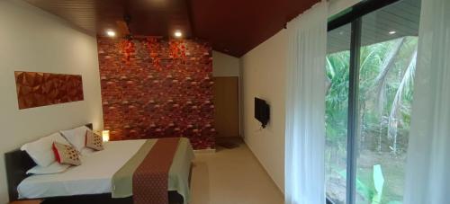 1 dormitorio con cama y pared de ladrillo en Walawal Bliss Farm Stay, en Vālāval