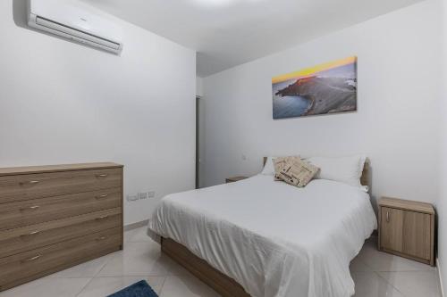a bedroom with a bed and a painting on the wall at Marsaxlokk Two Bedroom Apartment 1 minute away from the seafront in Marsaxlokk