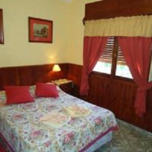 a bedroom with a bed with red pillows and a window at Hotel El Nogal La Falda in La Falda