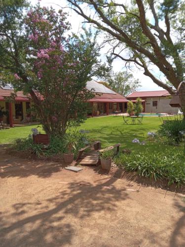 a park with a bench and a tree with flowers at A Cherry Lane Self Catering and B&B in Bloemfontein