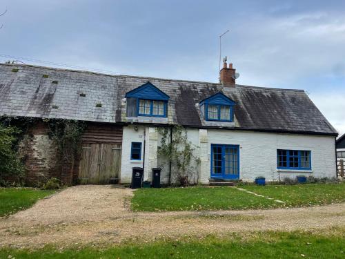 an old white house with blue windows on it at Cottages at Woodlands, Dormer in Wareham