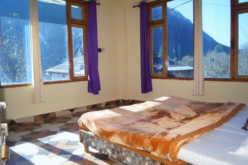 a bedroom with a bed in a room with windows at Apple Garden Katagla Kasol in Kasol