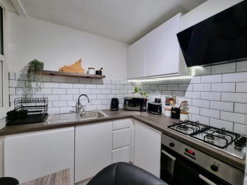 a white kitchen with a sink and a stove at Spacious and modern flat in Archway in London