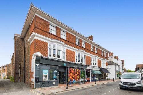 a red brick building with a store on a street at Ascot House Apartment in Hurstpierpoint