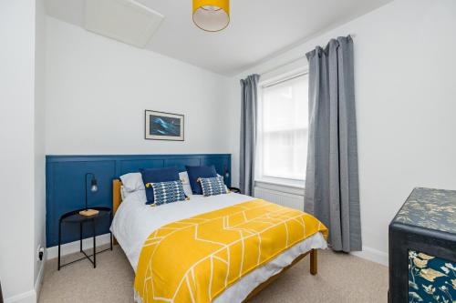 a bedroom with a yellow and blue bed and a window at Ascot House Apartment in Hurstpierpoint