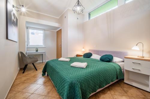 Un dormitorio con una cama verde con una silla y una ventana en Niezależny apartament z dużym parkingiem - Pogodna en Kudowa-Zdrój