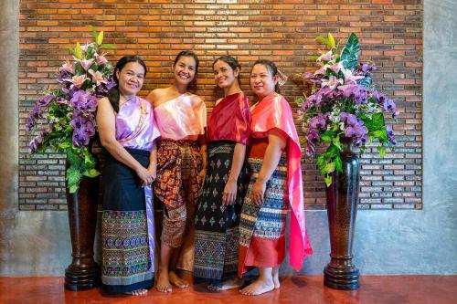 four women posing for a picture in front of a brick wall at Smilingface guesthouse in Sukhothai