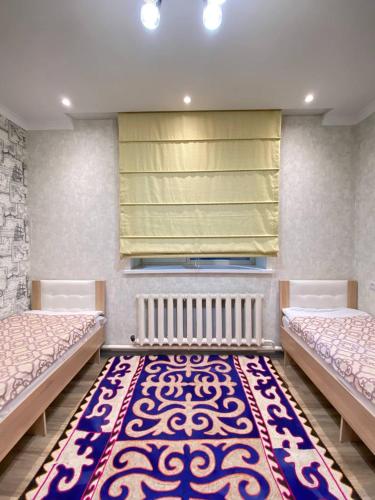 a room with two beds and a rug at Apart 23 in Karakol