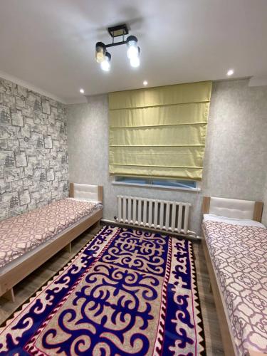 a room with two beds and a rug at Apart 23 in Karakol