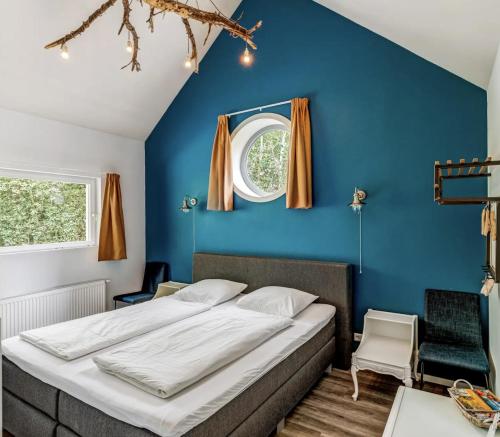 Bett in einem Zimmer mit blauer Wand in der Unterkunft Groepsaccommodatie / Familiehuis Bolle Buik, Borrel & Bed Appelscha in Appelscha