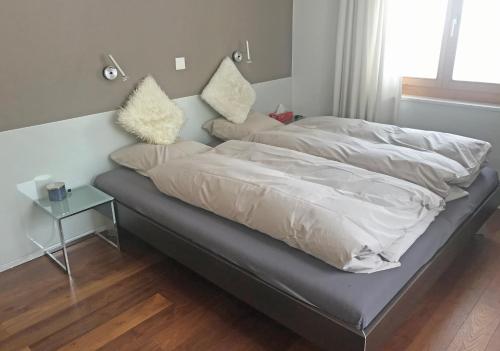 a bed with white sheets and pillows on it at Zentral, Ruhig, Sonnig, Modern in Lenzerheide