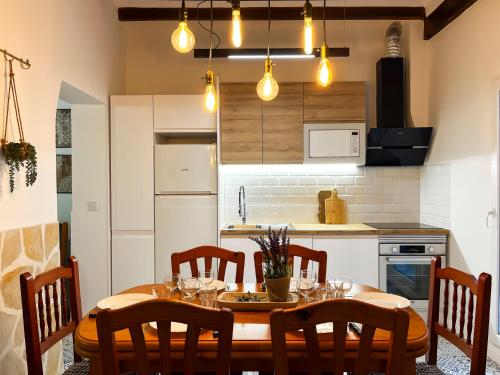 a kitchen with a wooden table and chairs and a kitchen with white appliances at Casa Rural La Travesía in Bolulla