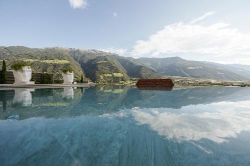 a pool of water with mountains in the background at Preidlhof Luxury Dolce Vita Resort in Naturno