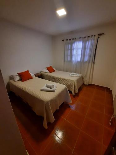 two beds in a room with a red tile floor at Nono Huasi Departamentos in Cafayate